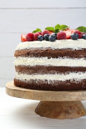 Photo of Delicious chocolate sponge cake with berries on light table, closeup