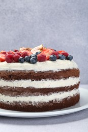 Photo of Delicious chocolate sponge cake with berries on light table, closeup