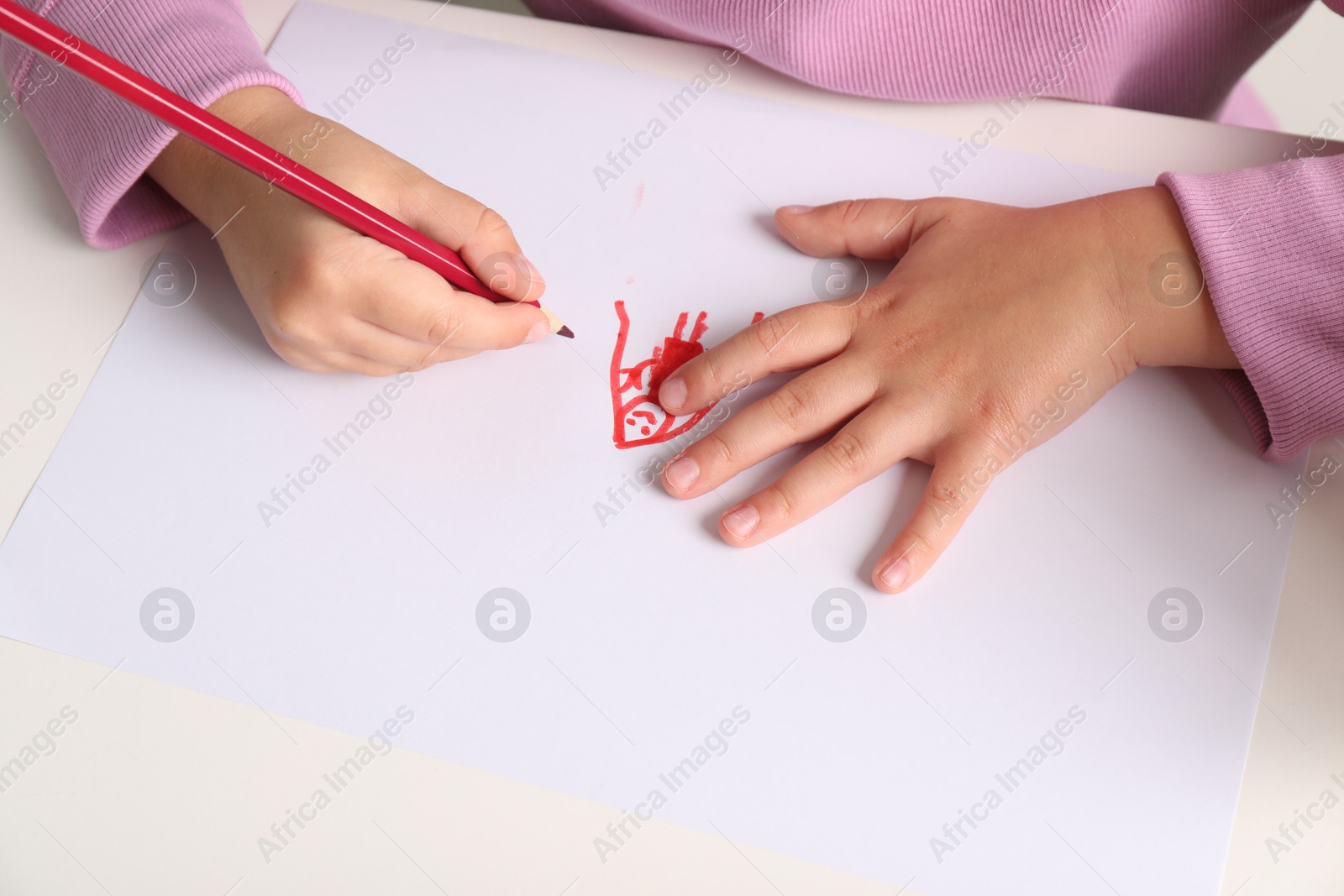 Photo of Little girl drawing his family at white table, closeup