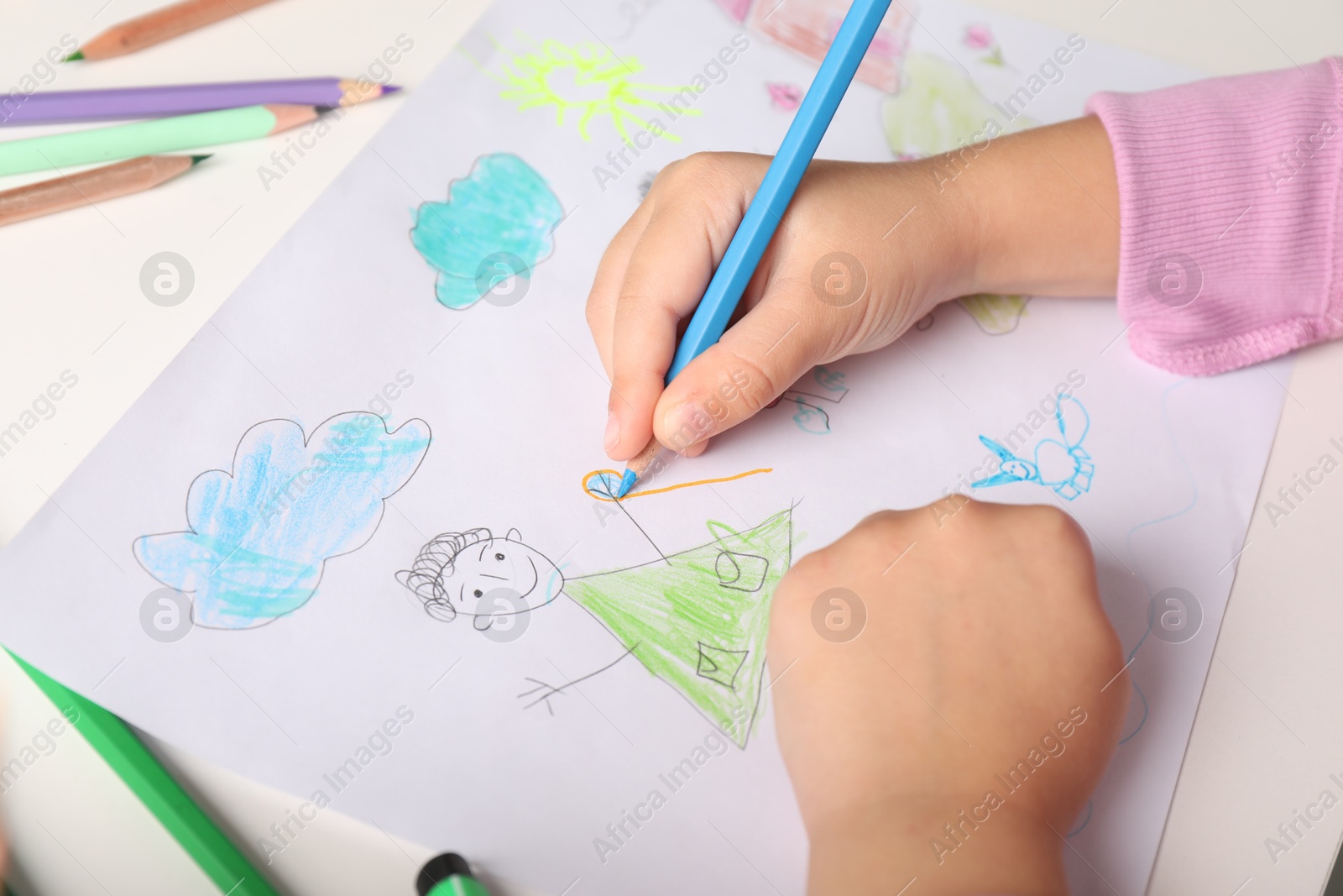 Photo of Little girl drawing his family at white table, closeup