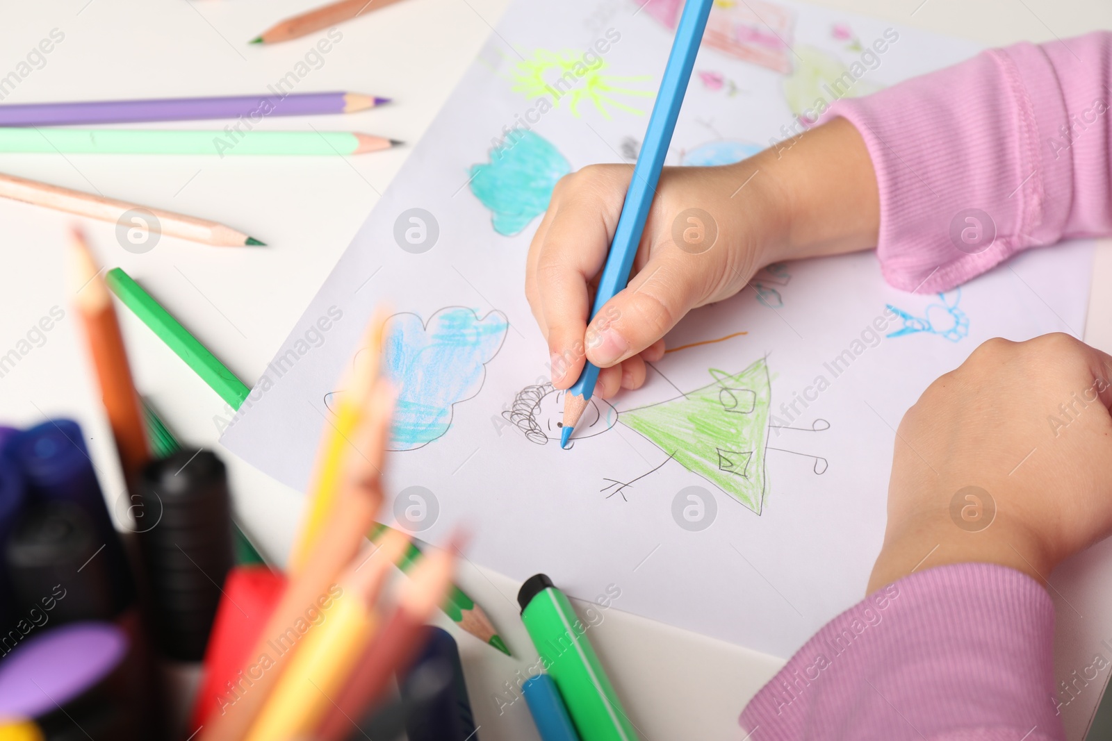 Photo of Little girl drawing his family at white table, closeup