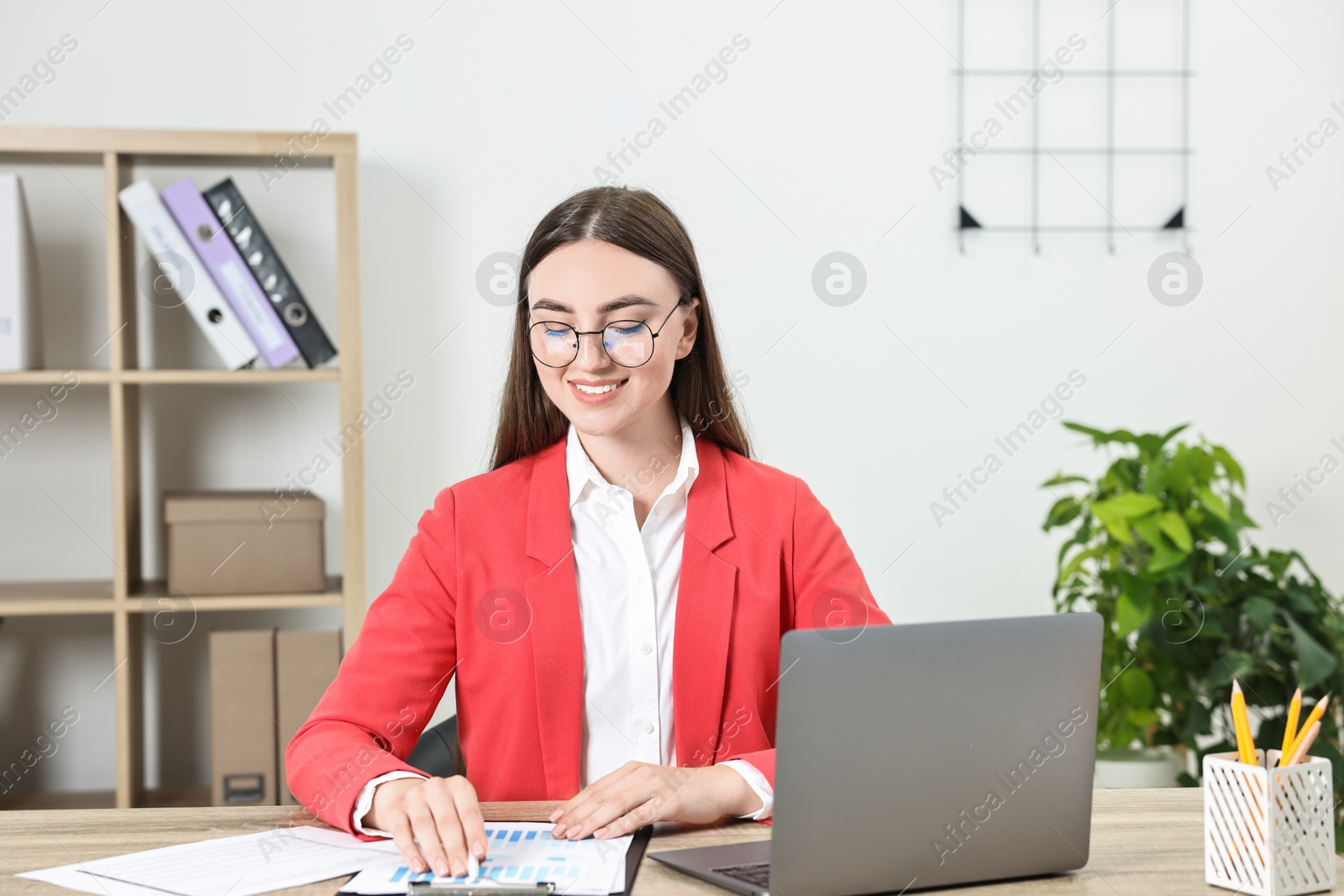 Photo of Budget planning. Young woman with papers and laptop at wooden table in office