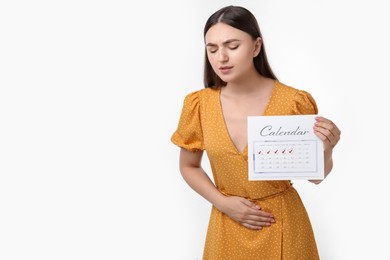 Photo of Woman holding calendar with marked menstrual cycle days and suffering from abdominal pain on white background, space for text