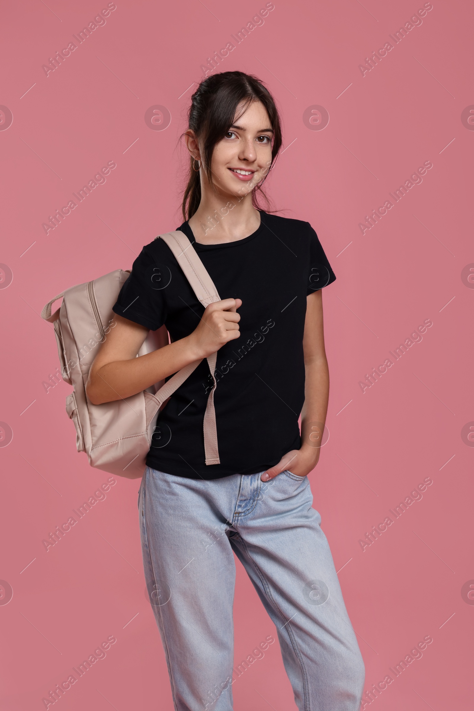 Photo of Portrait of cute teenage girl with backpack on pink background