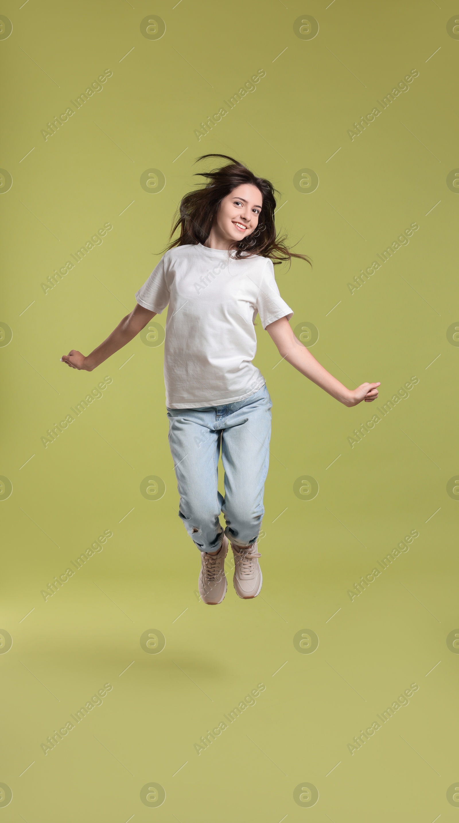 Photo of Cute teenage girl jumping on olive background