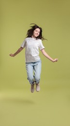 Photo of Cute teenage girl jumping on olive background