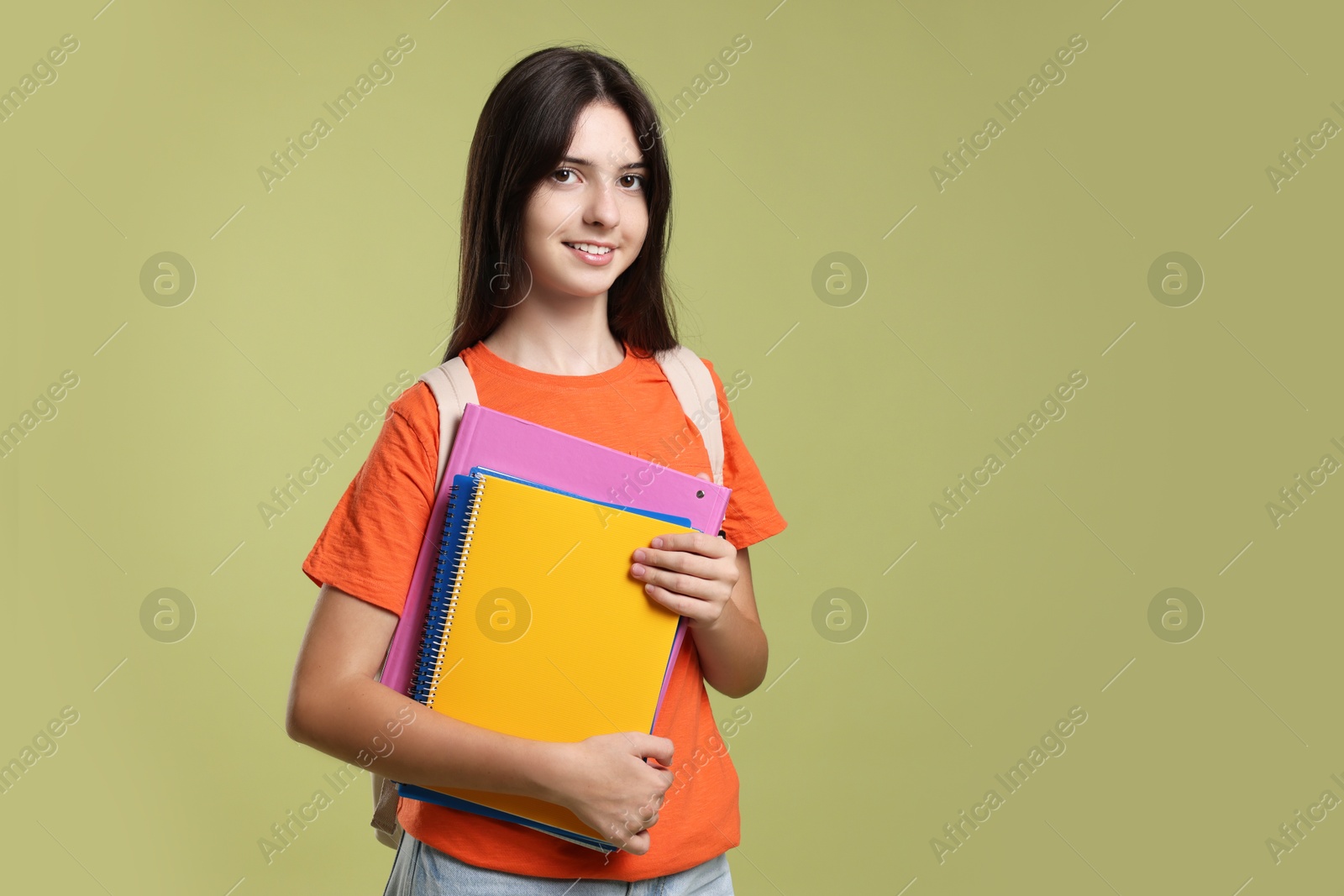 Photo of Portrait of cute teenage girl with backpack and books on olive background. Space for text