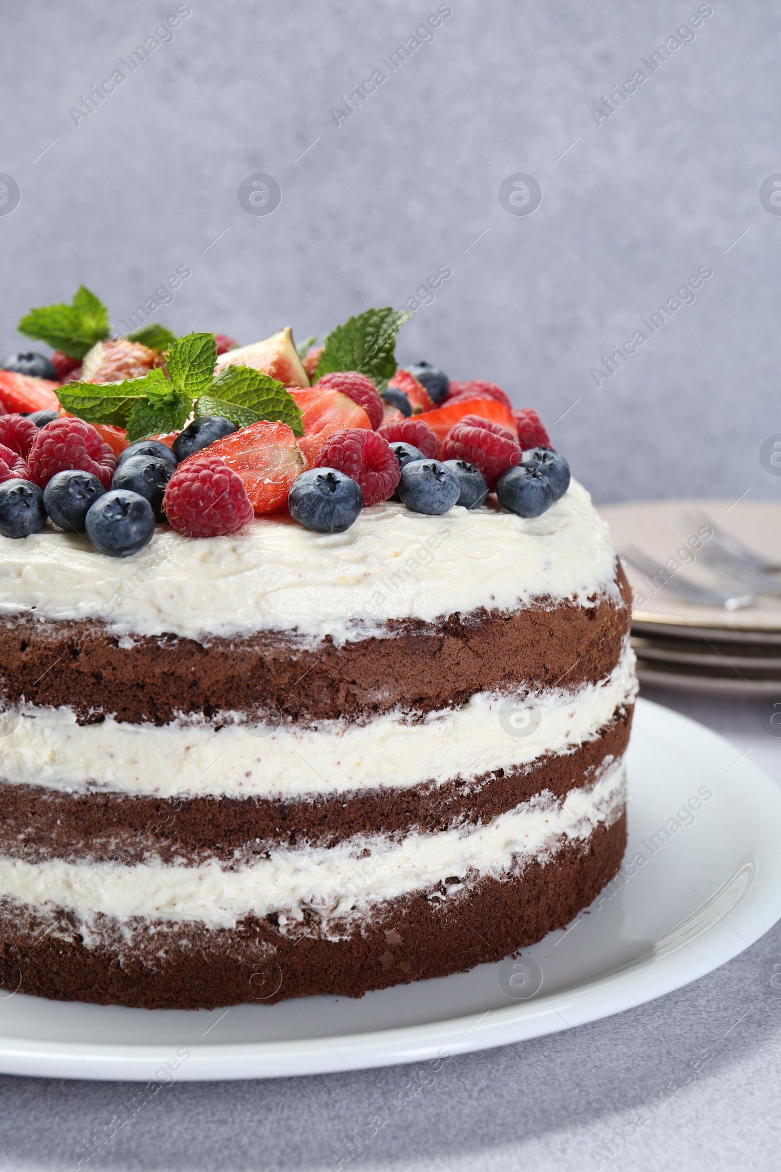 Photo of Delicious chocolate sponge cake with berries on light table, closeup