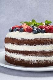 Photo of Delicious chocolate sponge cake with berries on light table, closeup