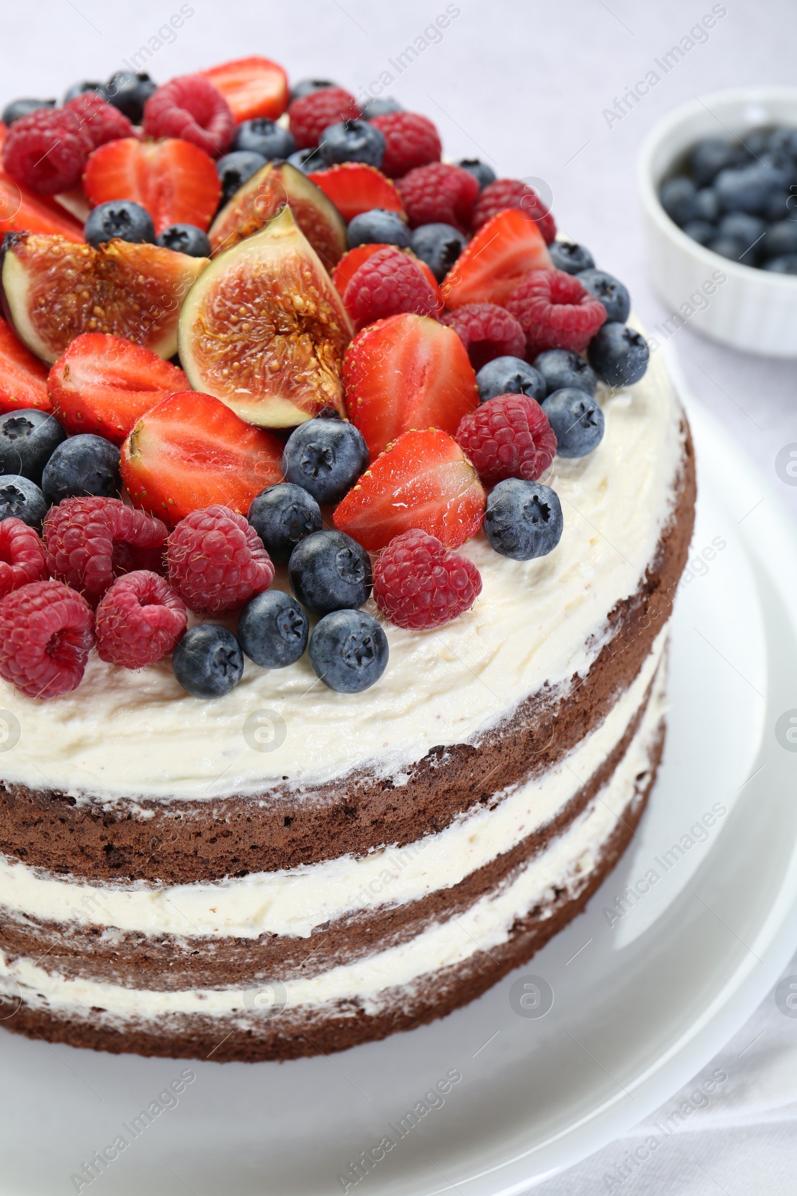 Photo of Delicious chocolate sponge cake with berries on light table, closeup