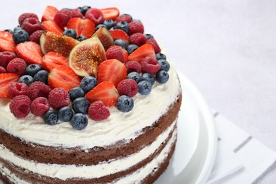 Delicious chocolate sponge cake with berries on light table, closeup