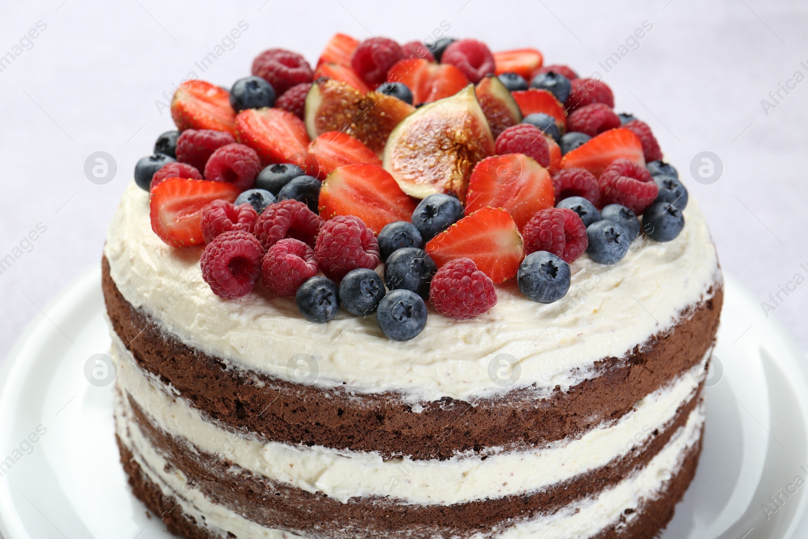 Photo of Delicious chocolate sponge cake with berries on light table, closeup