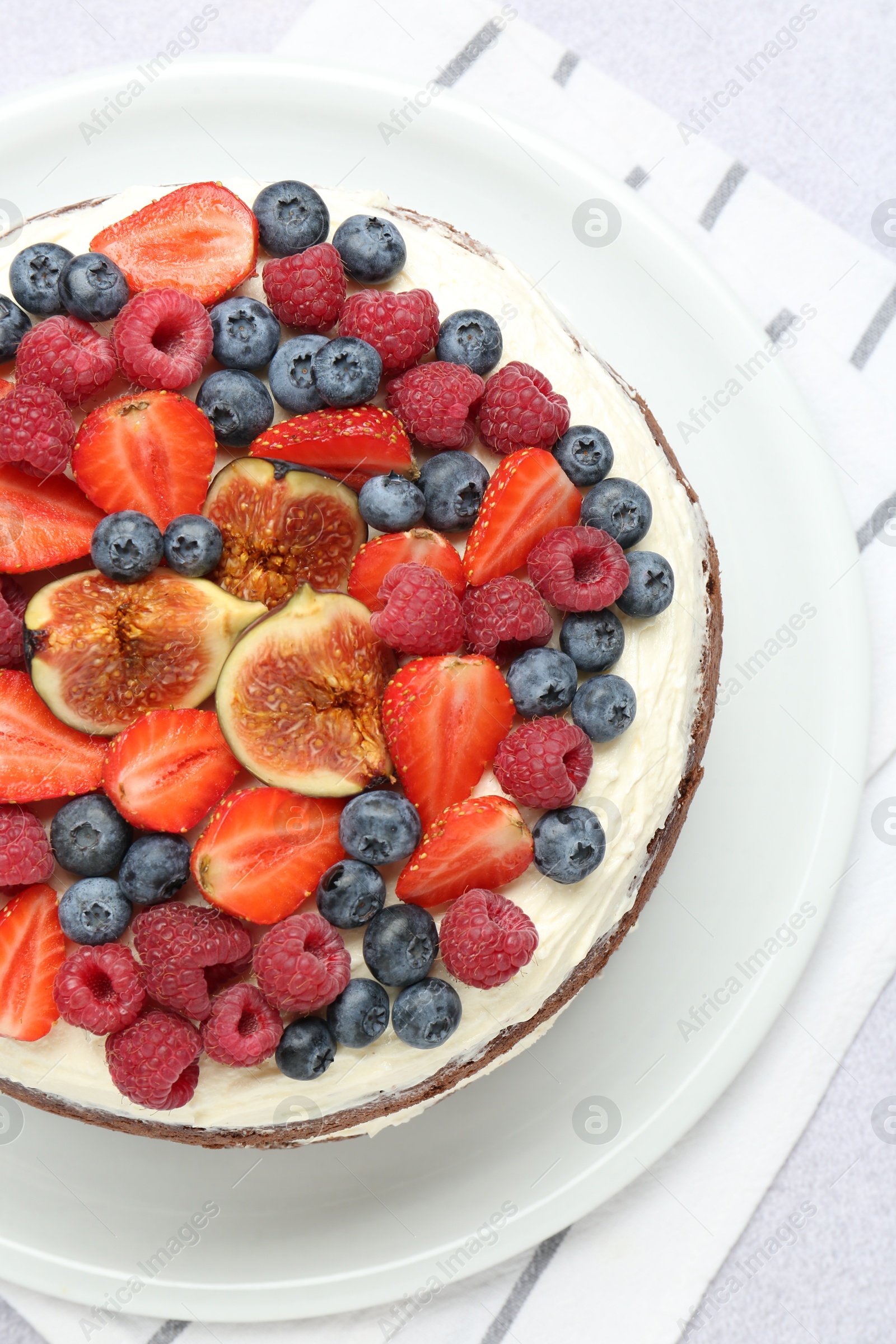 Photo of Delicious chocolate sponge cake with berries on light table, top view