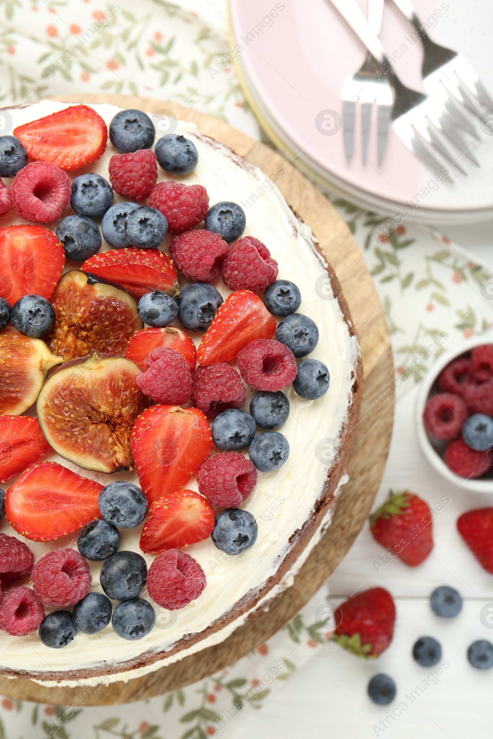 Photo of Delicious chocolate sponge cake with berries served on white wooden table, top view