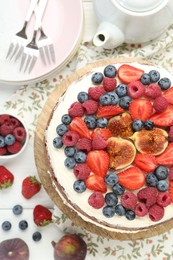 Photo of Delicious chocolate sponge cake with berries served on white wooden table, top view