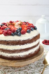 Delicious chocolate sponge cake with berries on table, closeup