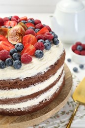 Delicious chocolate sponge cake with berries on table, closeup