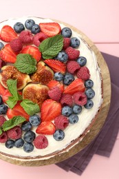 Photo of Delicious chocolate sponge cake with berries on pink table, top view