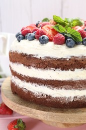 Delicious chocolate sponge cake with berries and mint on table, closeup