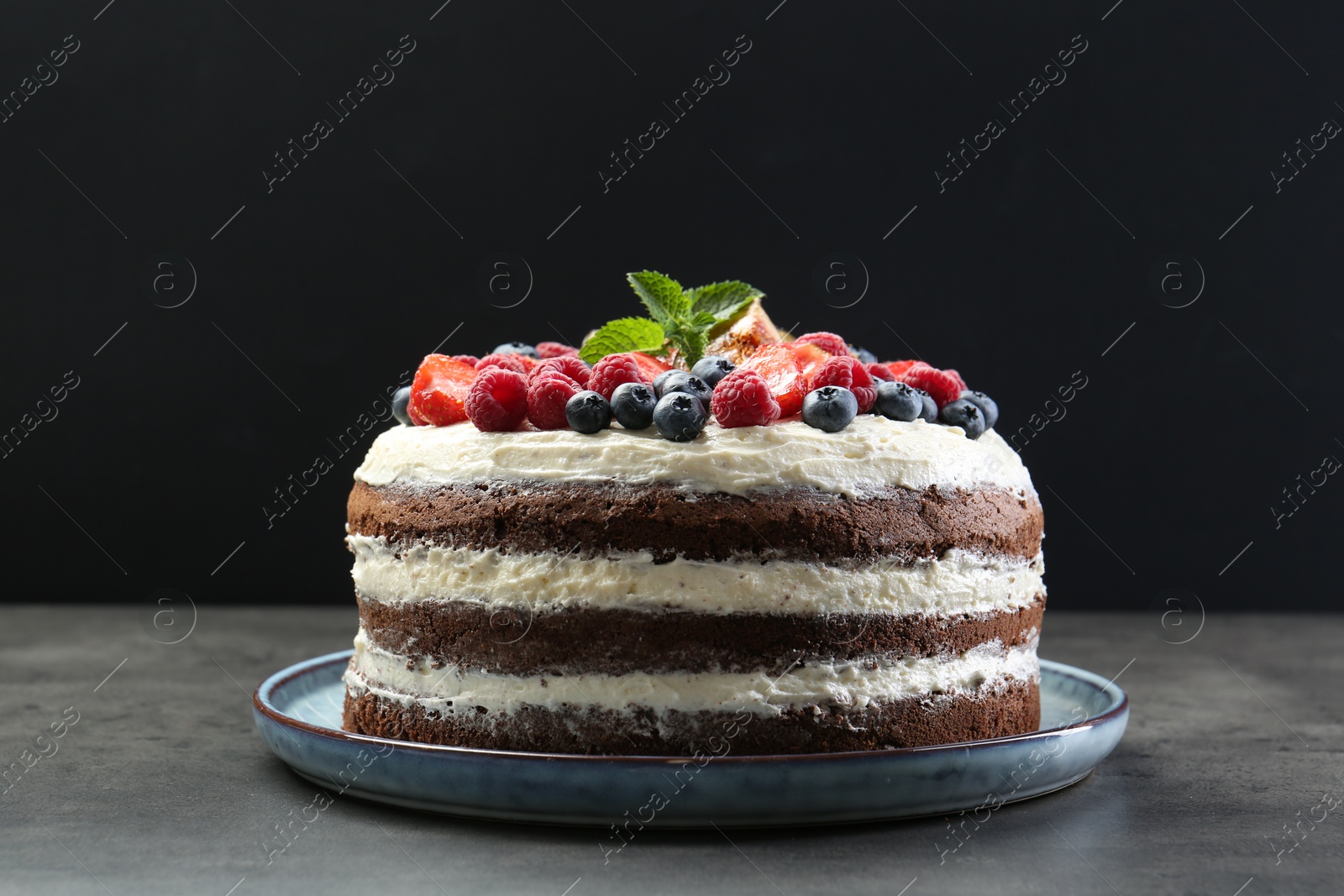 Photo of Delicious chocolate sponge cake with berries on grey table