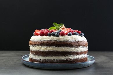 Delicious chocolate sponge cake with berries on grey table