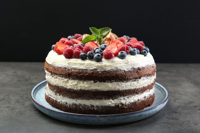 Delicious chocolate sponge cake with berries on grey table, closeup