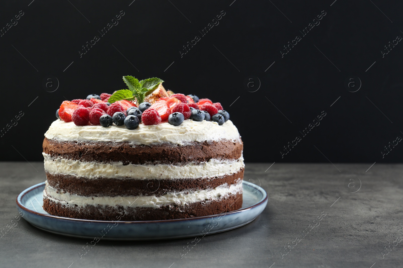 Photo of Delicious chocolate sponge cake with berries on grey table. Space for text