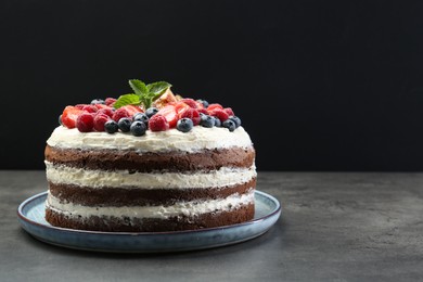 Photo of Delicious chocolate sponge cake with berries on grey table. Space for text