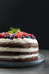 Delicious chocolate sponge cake with berries on grey table, closeup