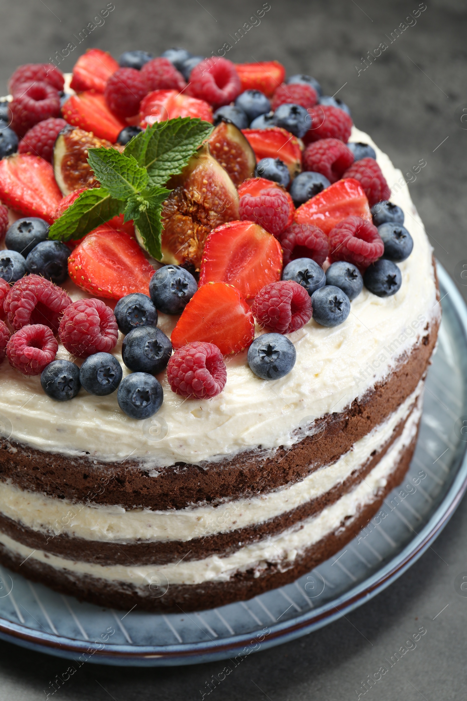 Photo of Delicious chocolate sponge cake with berries on grey table, closeup