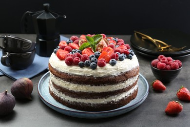 Photo of Delicious chocolate sponge cake with berries served on grey table