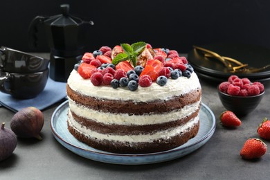 Photo of Delicious chocolate sponge cake with berries served on grey table