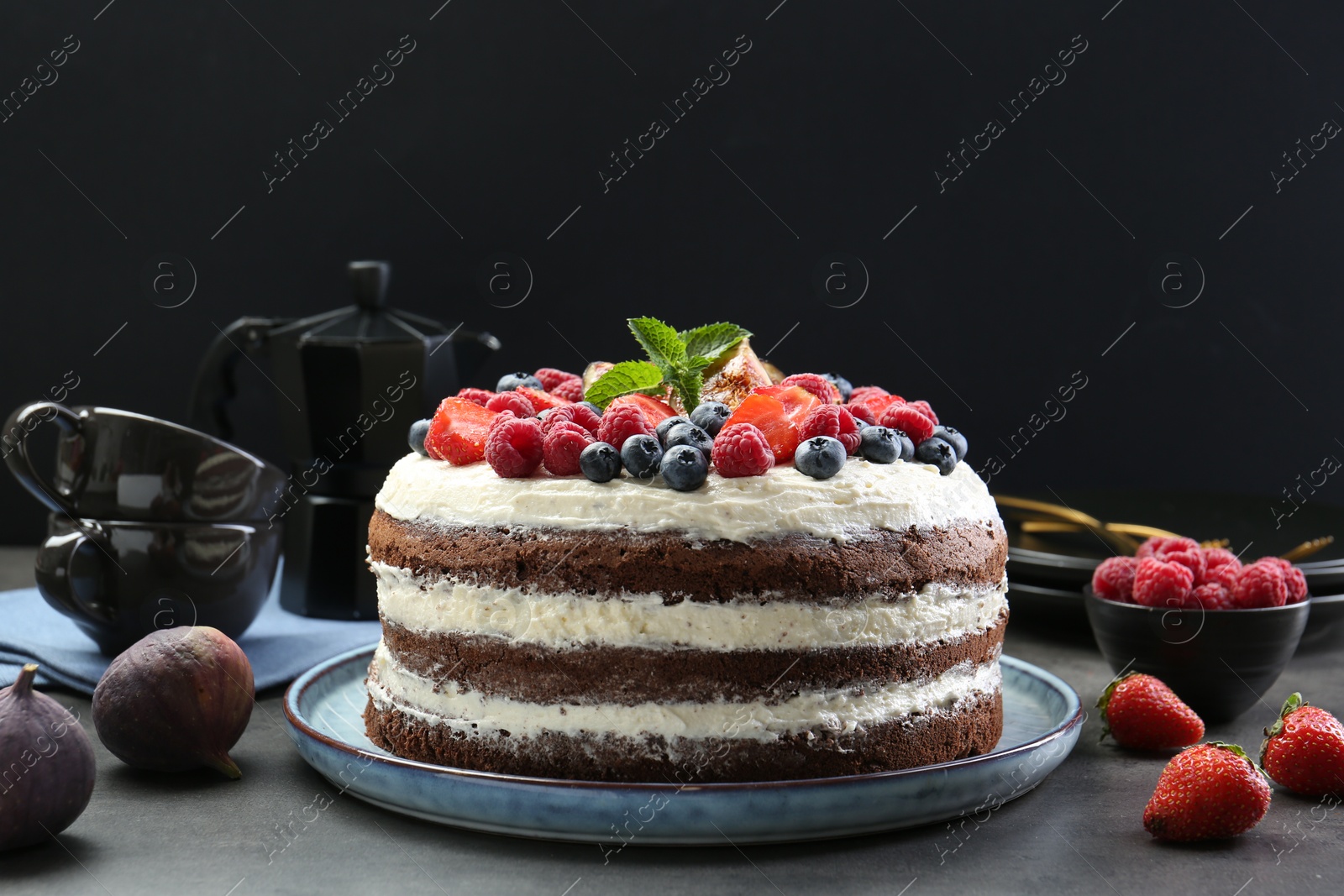 Photo of Delicious chocolate sponge cake with berries served on grey table