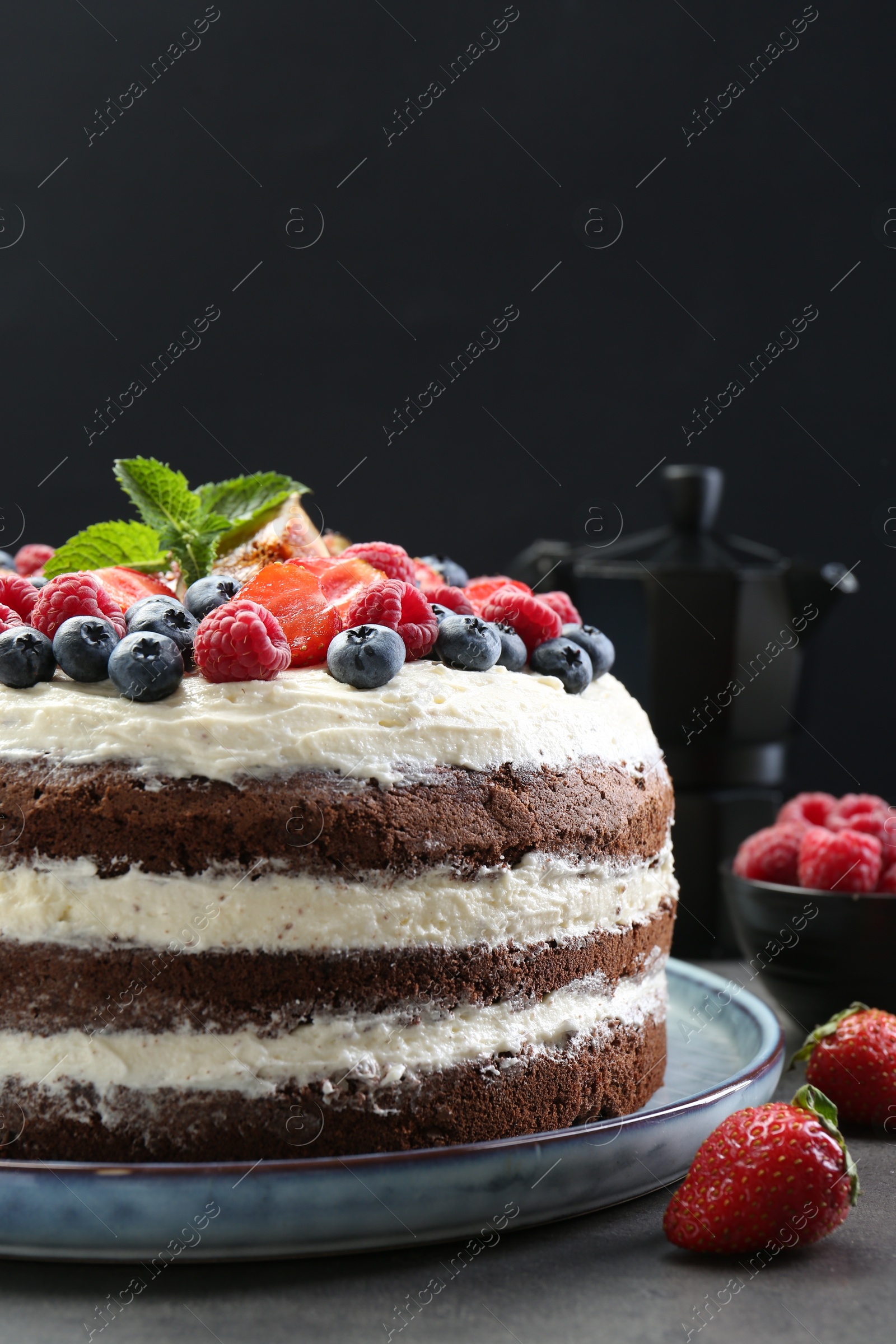 Photo of Delicious chocolate sponge cake with berries served on grey table, closeup