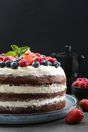 Delicious chocolate sponge cake with berries served on grey table, closeup