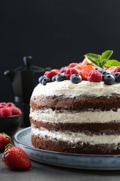 Photo of Delicious chocolate sponge cake with berries on grey table, closeup