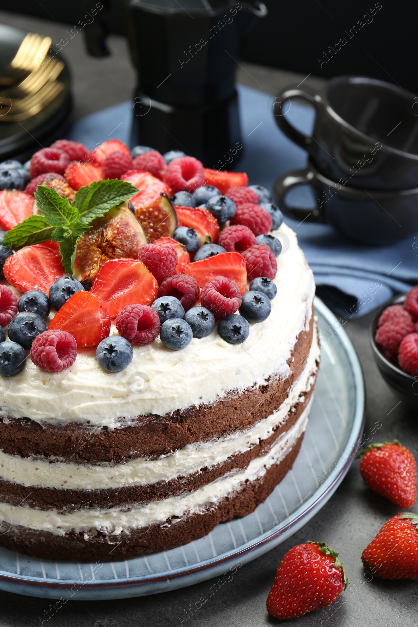 Photo of Delicious chocolate sponge cake with berries served on grey table, closeup