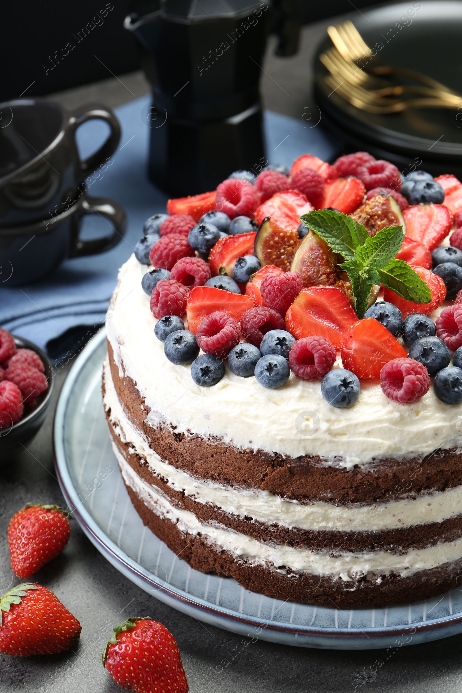 Photo of Delicious chocolate sponge cake with berries served on grey table, closeup