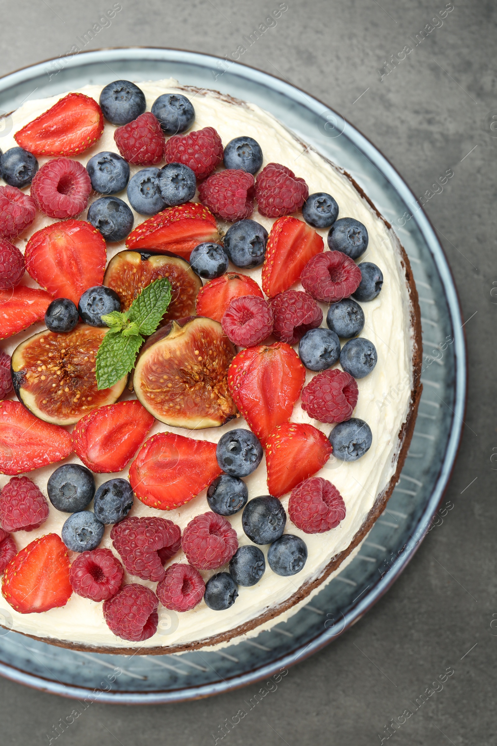 Photo of Delicious chocolate sponge cake with berries on grey table, top view