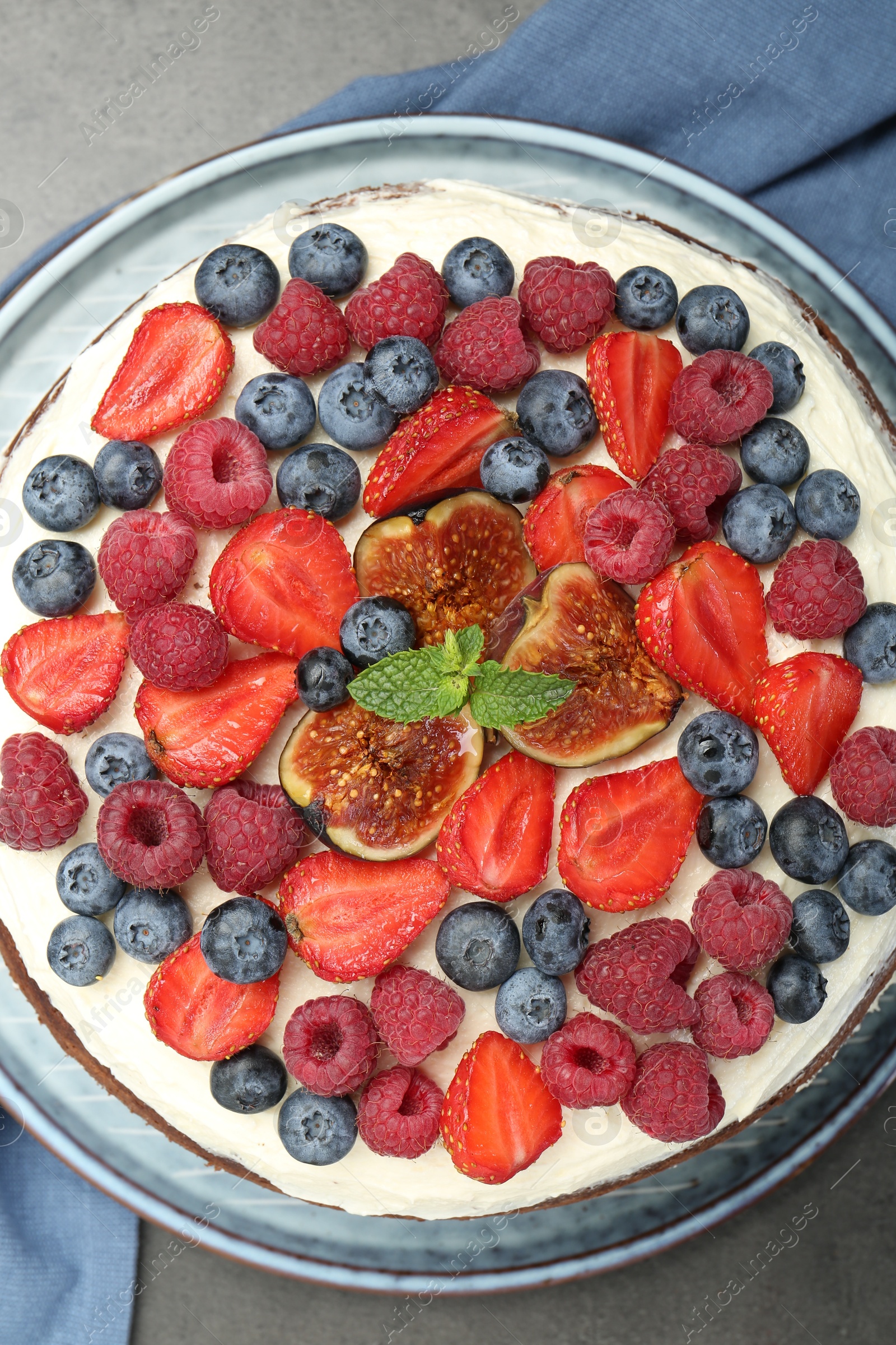 Photo of Delicious chocolate sponge cake with berries on grey table, top view