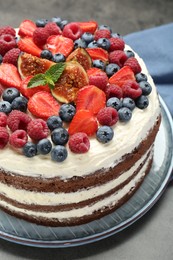 Photo of Delicious chocolate sponge cake with berries on grey table, closeup