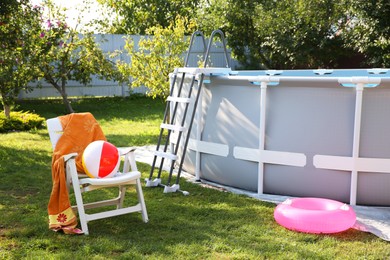 Photo of Above ground swimming pool, folding chair, towel, inflatable ring and ball in backyard