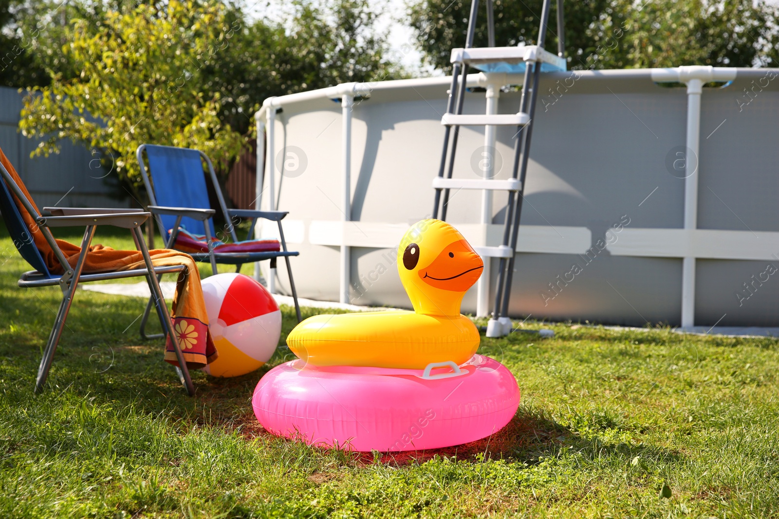 Photo of Above ground swimming pool, folding chairs, towel, inflatable rings and ball in backyard