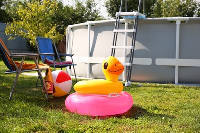 Above ground swimming pool, folding chairs, towel, inflatable rings and ball in backyard