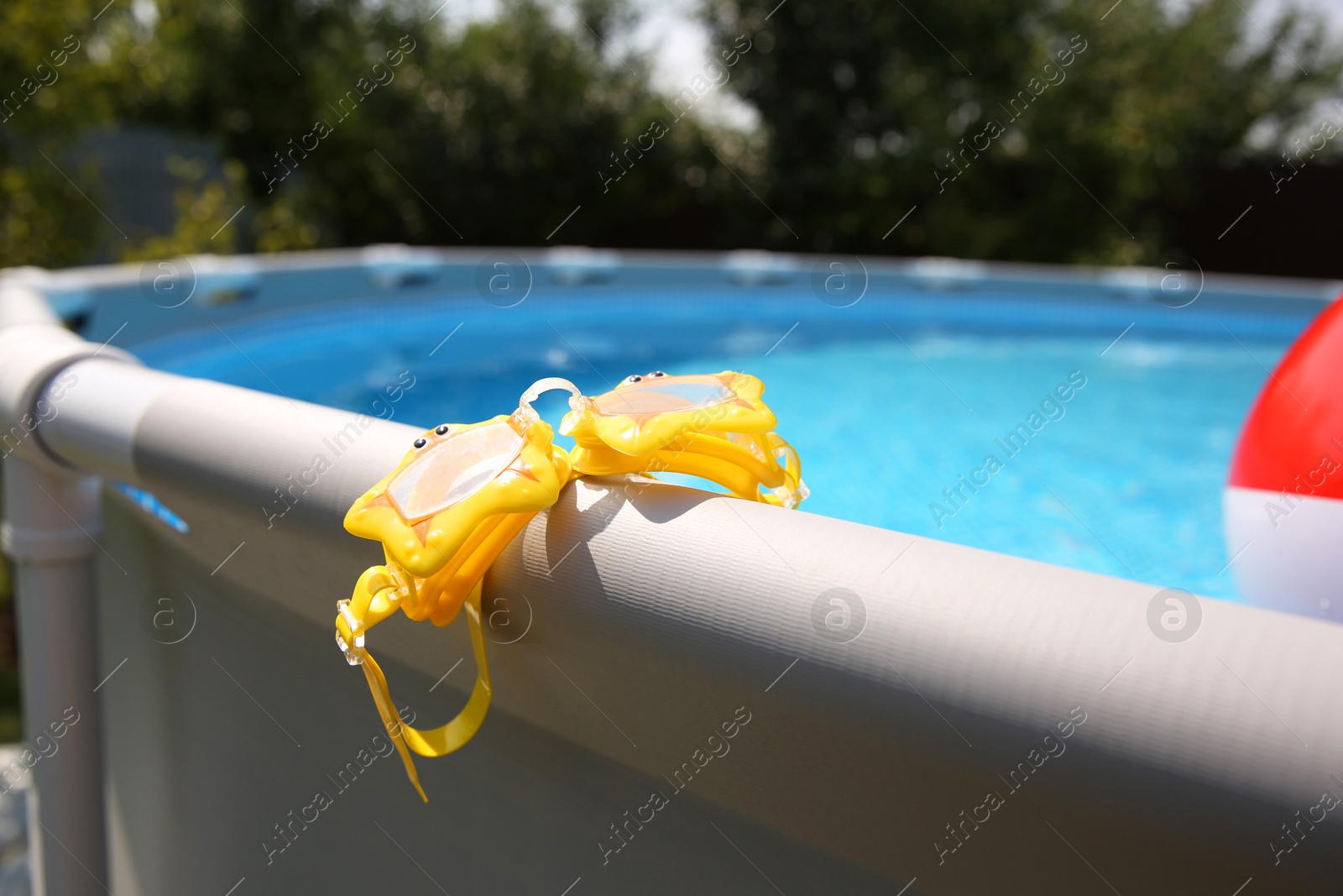 Photo of Swimming goggles for kids on top rail of pool, closeup