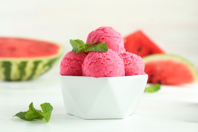 Photo of Scoops of tasty watermelon sorbet with mint in bowl on white table, closeup