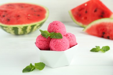 Photo of Scoops of tasty watermelon sorbet with mint in bowl on white table