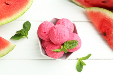 Scoops of tasty watermelon sorbet with mint in bowl and fresh fruit on white wooden table, flat lay