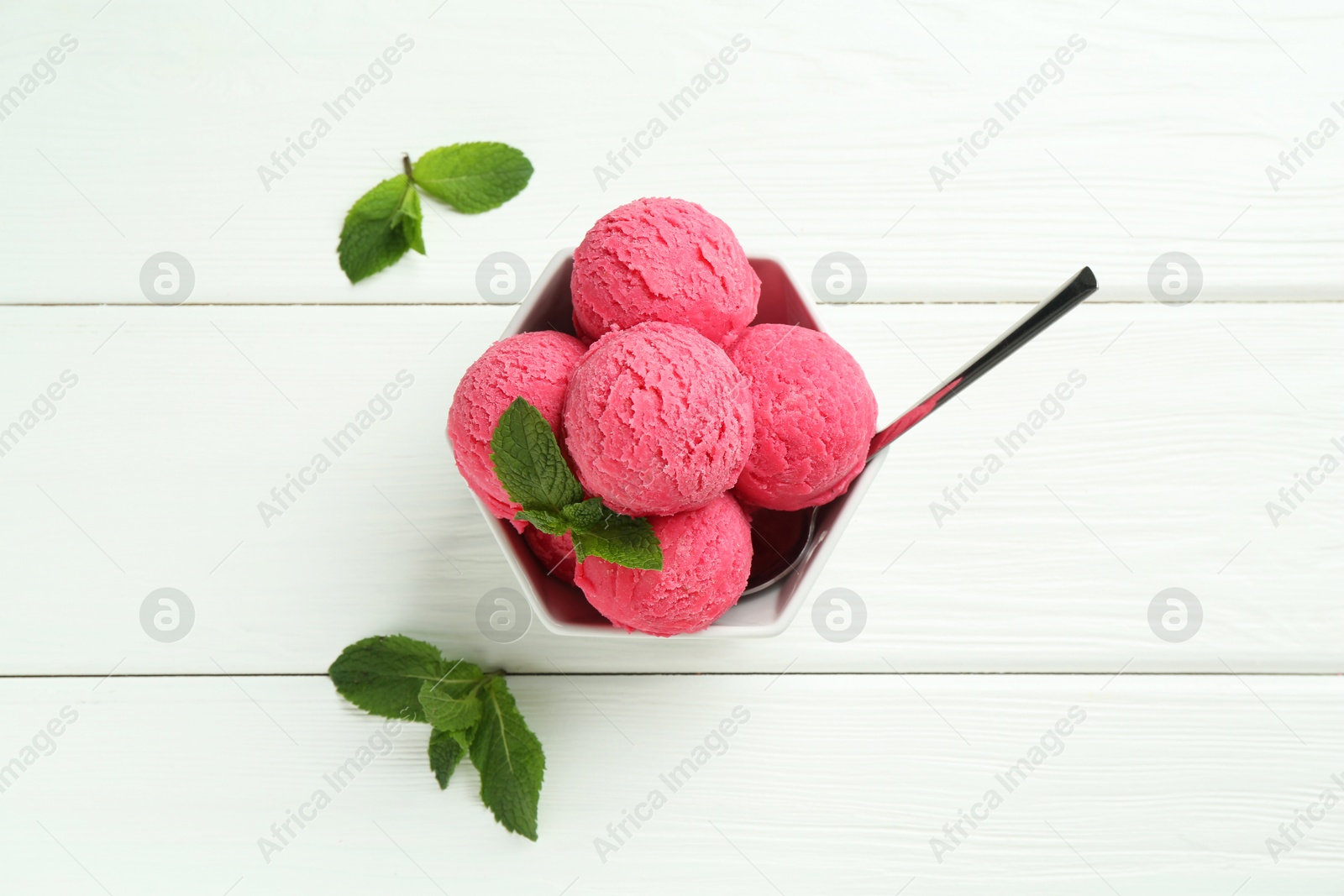 Photo of Scoops of tasty watermelon sorbet with mint and spoon in bowl on white wooden table, flat lay