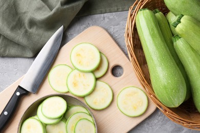 Photo of Fresh zucchinis and knife on grey textured table, flat lay